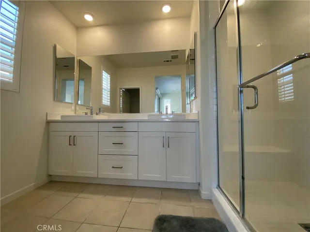 a bathroom with a double vanity sink mirror and shower