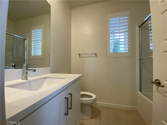 a bathroom with a granite countertop toilet a sink and a mirror