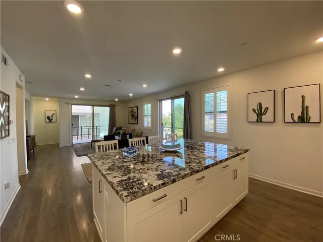 a large dining hall with stainless steel appliances granite countertop a sink dishwasher a couches with wooden floor and floor to ceiling window