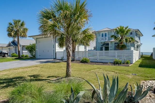 a palm tree sitting in front of a house with a yard