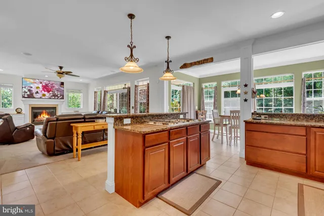 a large kitchen with kitchen island granite countertop a stove a sink a dining table and chairs with the living room view