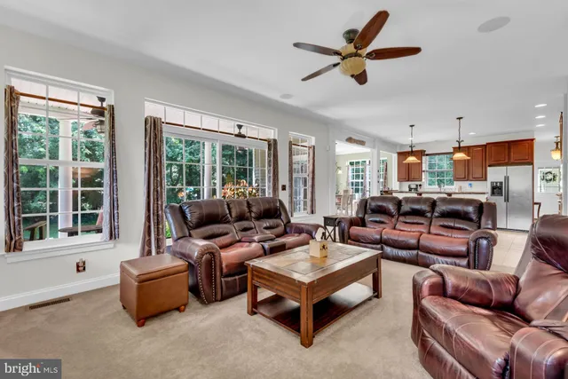 a living room with furniture ceiling fan and a large window