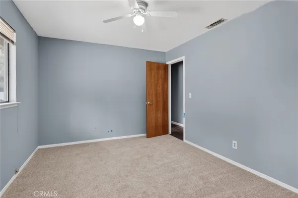 an empty room with a ceiling fan and window