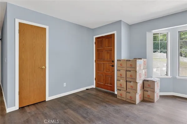 a view of an empty room with wooden floor and windows