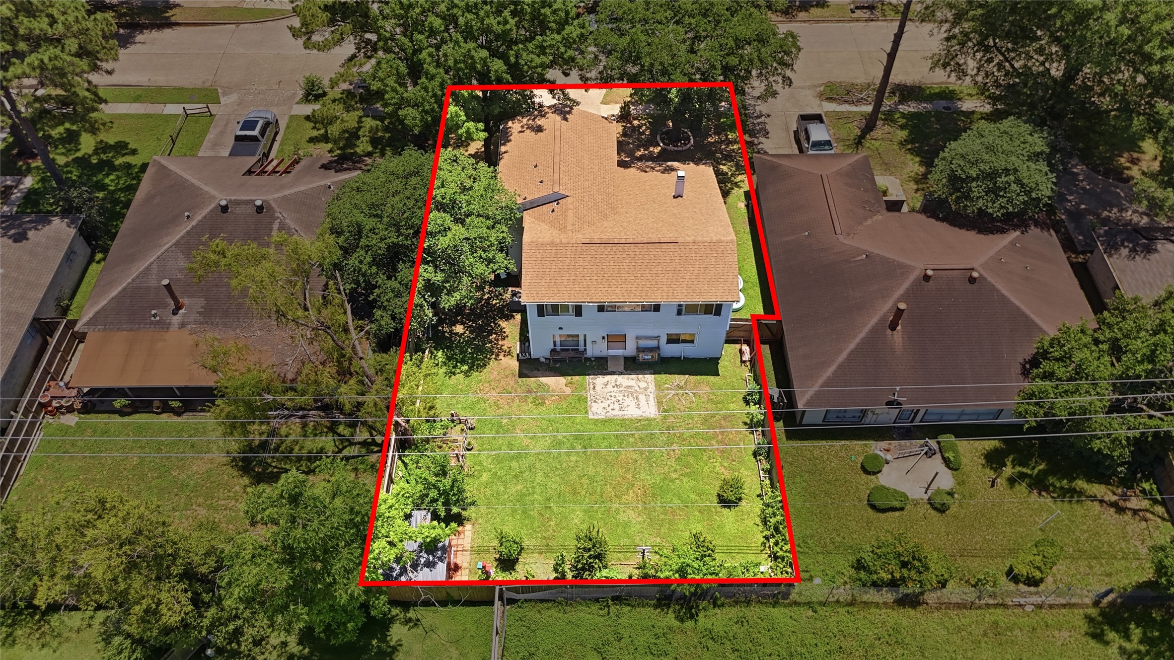 4718 Temple Bell Drive Spring, TX 77388 - Photo 45 of 50 This aerial view showcases a two-story home with a spacious backyard, outlined in red for clarity. The property is nestled between two single-story houses in a green, tree-lined neighborhood. The backyard features a patio area, ideal for outdoor activities.