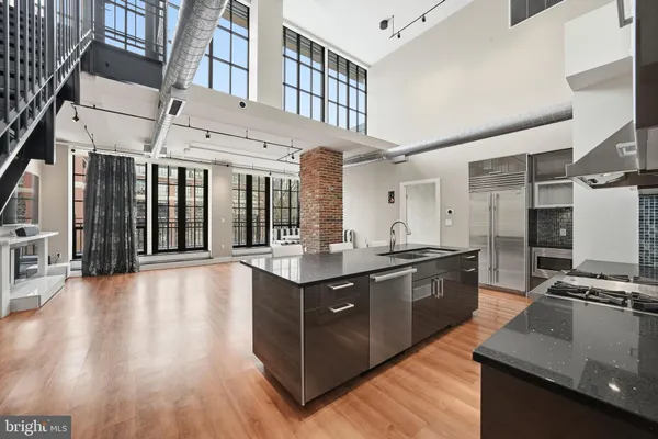 a large kitchen with stainless steel appliances granite countertop a large stove a sink dishwasher and a oven with wooden floors