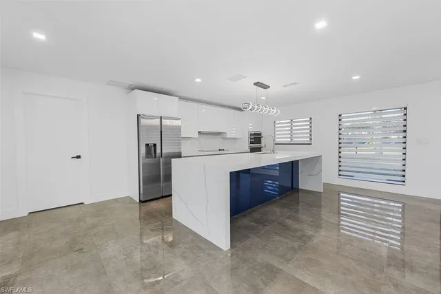 a kitchen with stainless steel appliances a refrigerator sink and white cabinets