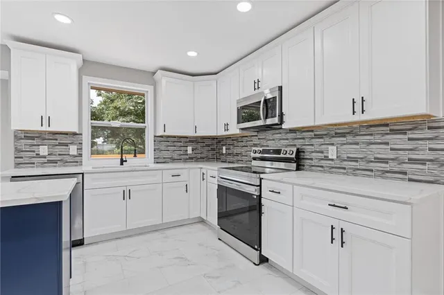 a kitchen with cabinets appliances a sink and a window