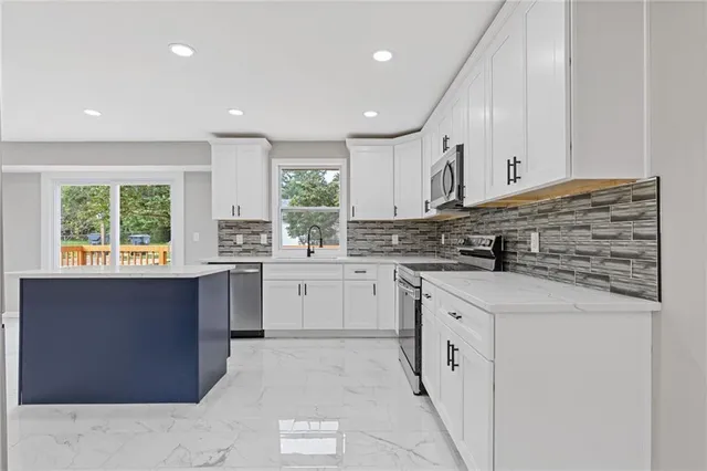 a kitchen with stainless steel appliances granite countertop a stove a sink and a microwave