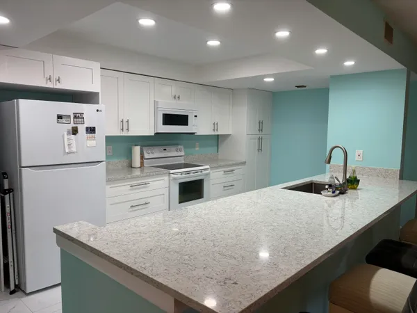 a kitchen with kitchen island a sink stainless steel appliances and refrigerator