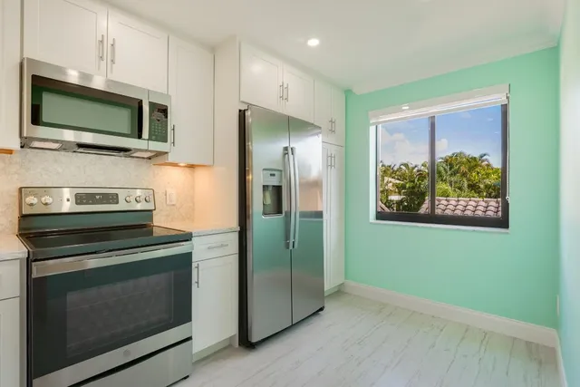 a view of a kitchen with fridge and wooden floor