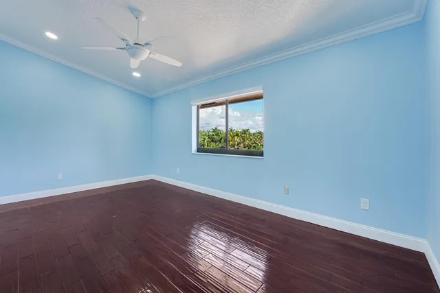 an empty room with wooden floor chandelier fan and windows