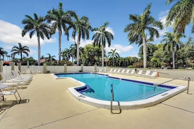 a view of a swimming pool with a chair and palm trees
