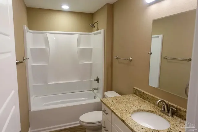a bathroom with a granite countertop sink toilet and shower