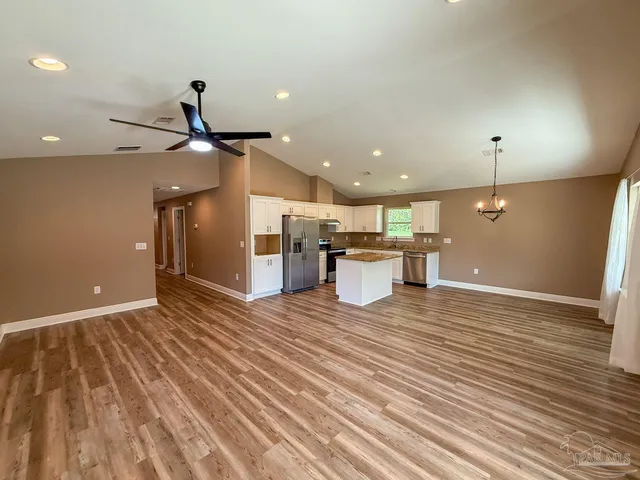a view of a room with kitchen island stainless steel appliances wooden floor and living room view