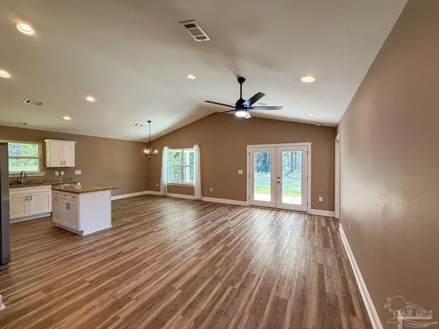 a view of an empty room with window and wooden floor