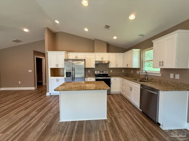 a large kitchen with stainless steel appliances granite countertop a lot of counter space and wooden floors