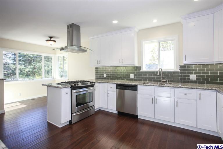 4465 Rising Hill Road Altadena, CA 91001 - Photo 18 of 45 a kitchen with granite countertop white cabinets and wooden floor