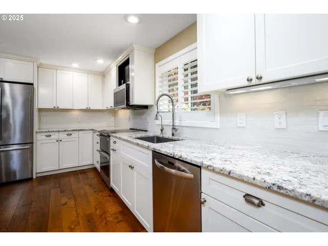 a kitchen with a sink cabinets stainless steel appliances and a window