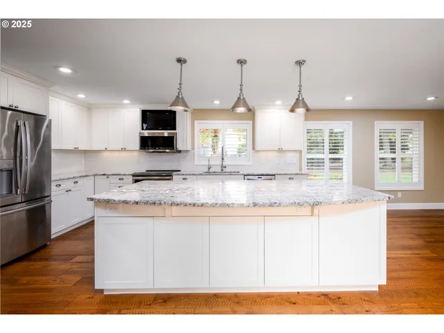 a kitchen with stainless steel appliances granite countertop a sink a stove a refrigerator a center island and cabinets