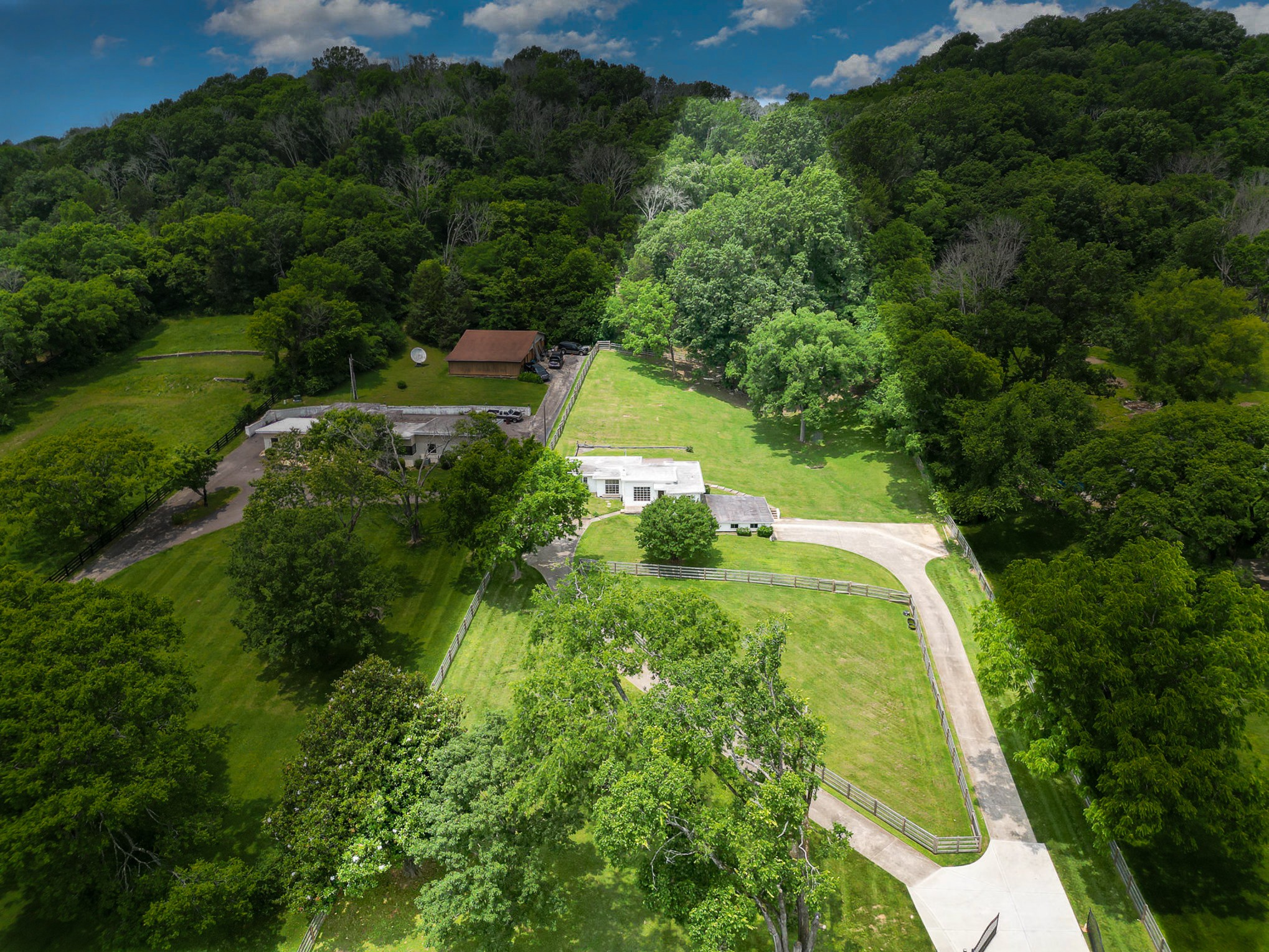 an aerial view of residential house with outdoor space and trees all around