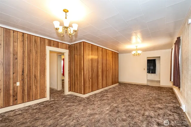 an empty room with kitchen view and a chandelier