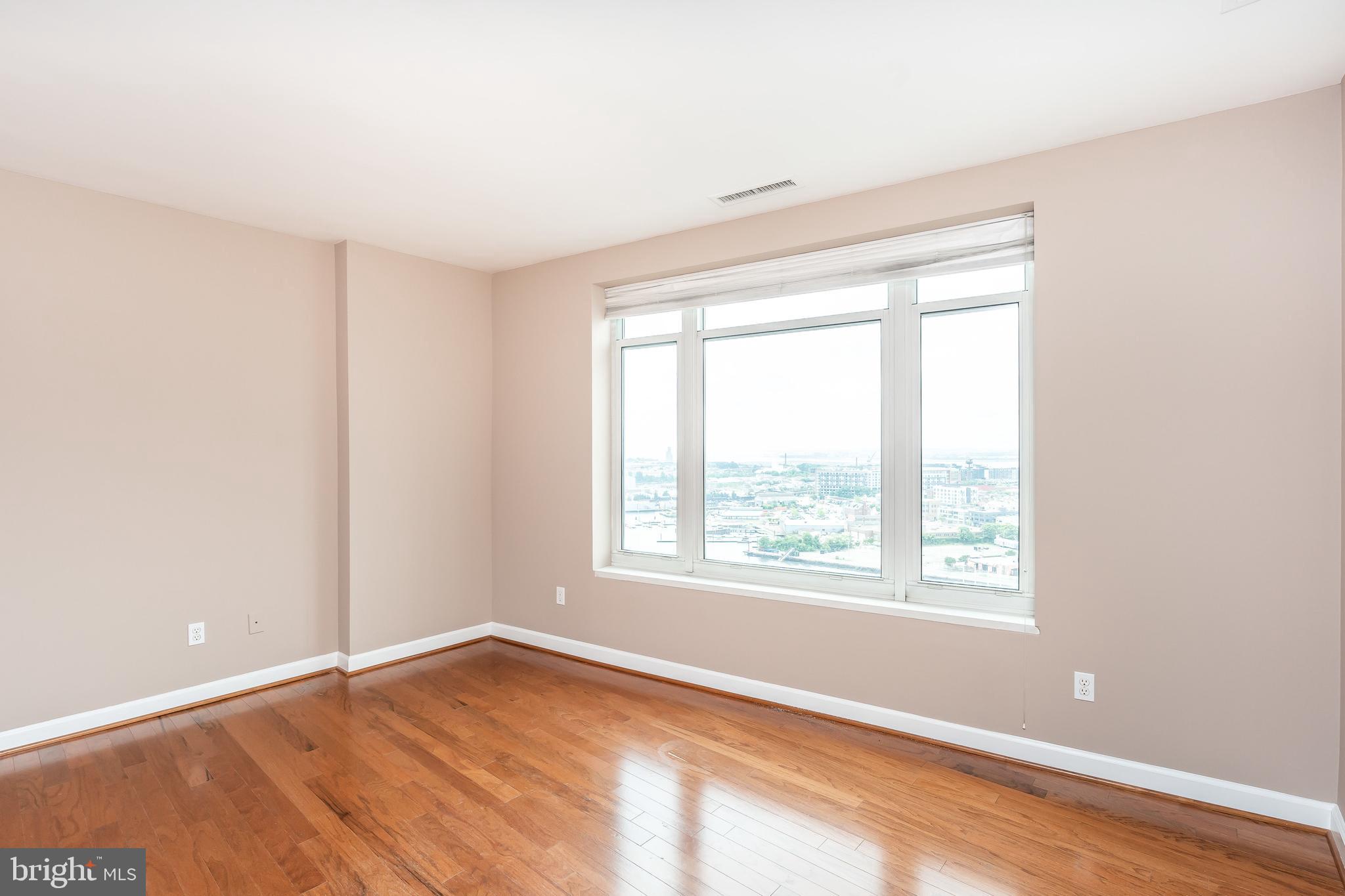 100 Harborview Drive, Unit 1908 Baltimore, MD 21230 - Photo 9 of 60 a view of an empty room with wooden floor and a window