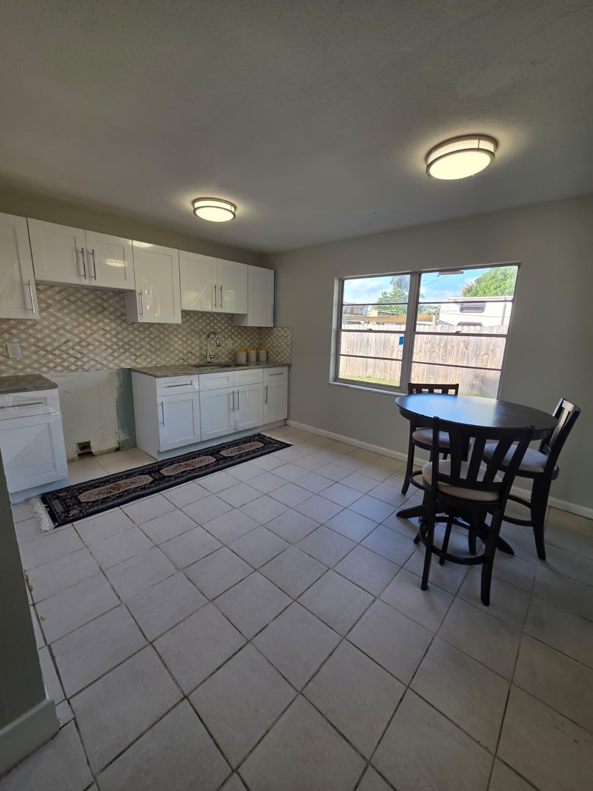 3386 Rudolph Road Lake Worth Beach, FL 33461 - Photo 15 of 25 a kitchen with a table chairs sink and cabinets