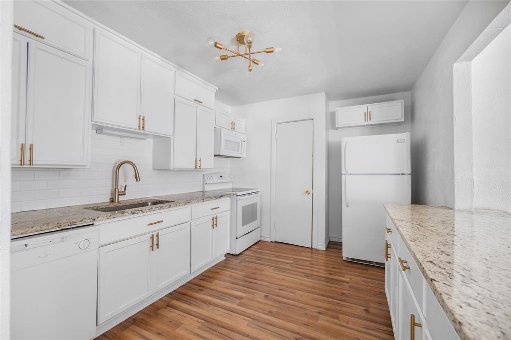 4723 Victor Street, Unit B Dallas, TX 75246 - Photo 4 of 12 Contemporary kitchen featuring white cabinetry with gold-tone hardware, granite-style countertops, white subway tile backsplash, and wood-finish flooring