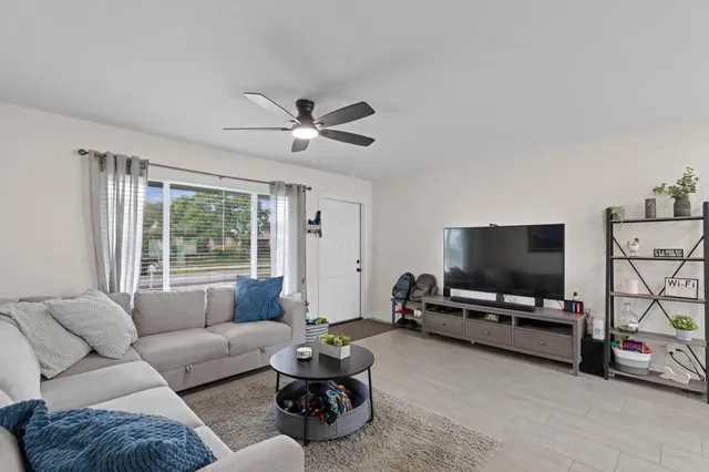 a living room with furniture ceiling fan and a window