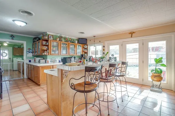 a dining hall with stainless steel appliances kitchen island granite countertop a table and chairs in it