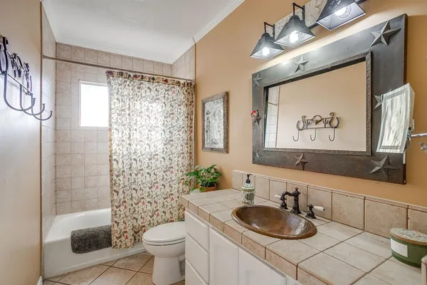 a bathroom with a granite countertop sink a mirror a toilet and a shower curtain
