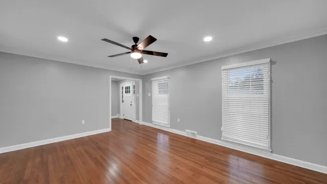 a view of an empty room with a window and wooden floor