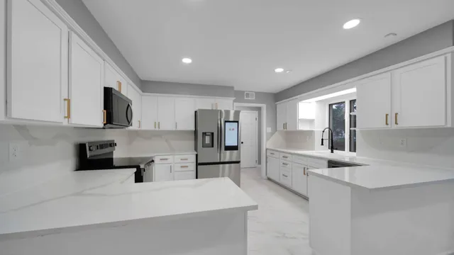 a large white kitchen with stainless steel appliances