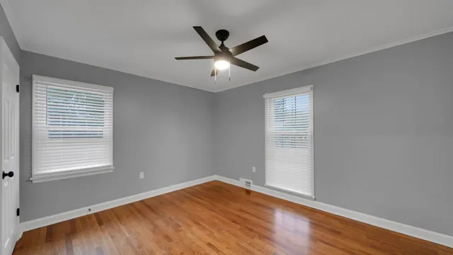 a view of an empty room with wooden floor and a window