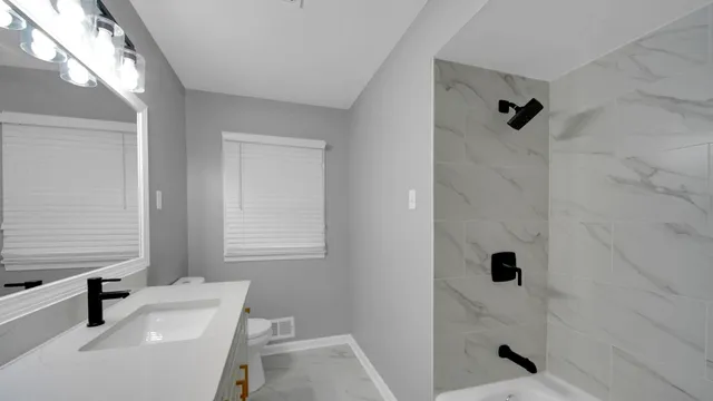 a bathroom with a sink a toilet a window and shower