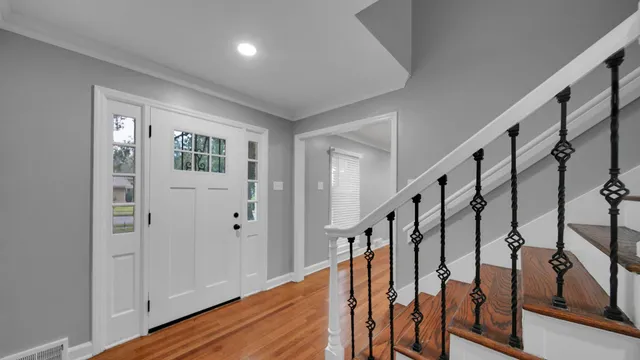 a view of staircase with lots of frames on wall and wooden floor