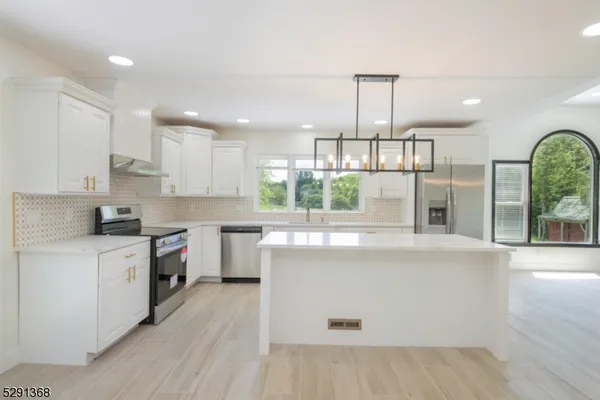 a kitchen with kitchen island a counter top a stove a refrigerator and cabinets