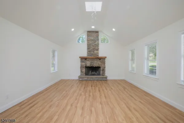 a view of an empty room with wooden floor fireplace and a window