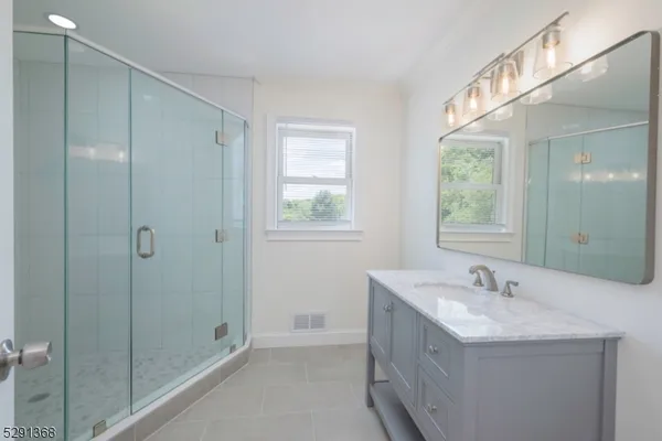 a bathroom with a granite countertop sink a mirror and a shower