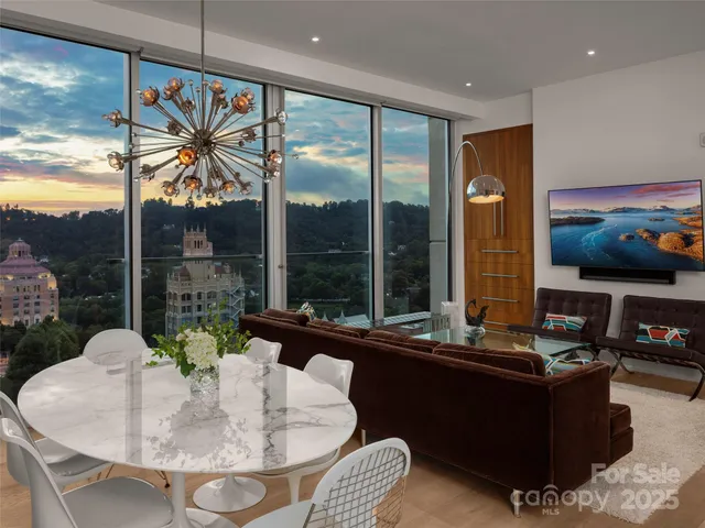 a living room with large couches and dining table with garden view