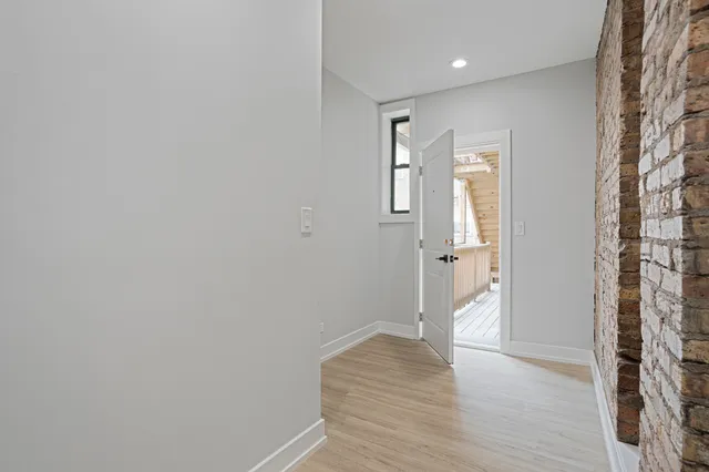 a view of a hallway with wooden floor and a bathroom