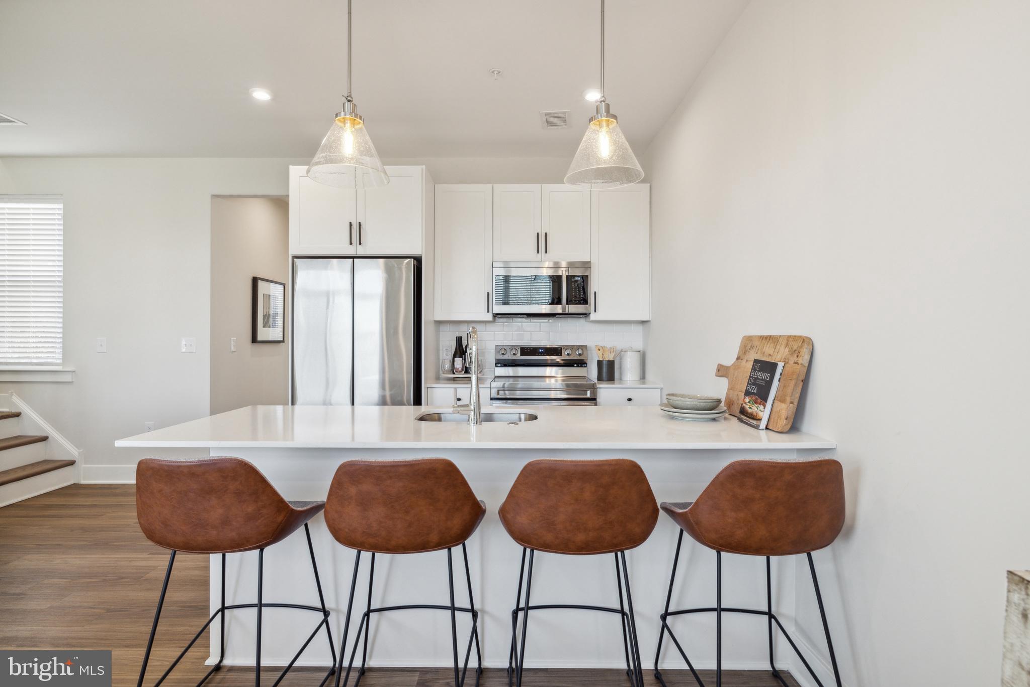 17 Mainland Road, Unit 216 Harleysville, PA 19438 - Photo 6 of 23 a kitchen with stainless steel appliances granite countertop a dining table chairs and a refrigerator