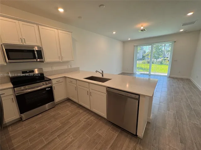 a kitchen with stainless steel appliances a refrigerator a sink a stove a microwave and cabinets