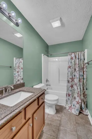 a bathroom with a granite countertop sink mirror vanity and toilet