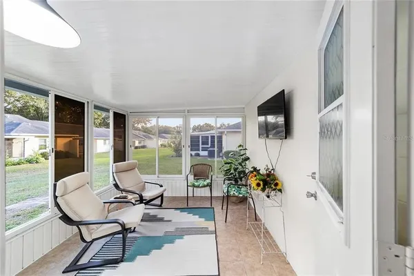 a living room with furniture a flat screen tv and floor to ceiling window