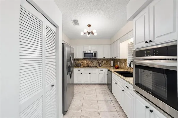a kitchen with granite countertop white cabinets and white appliances