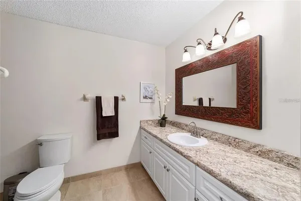a bathroom with a granite countertop sink vanity mirror and toilet