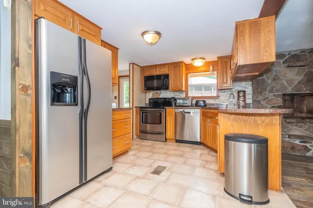 a kitchen with stainless steel appliances granite countertop a refrigerator a stove and a sink