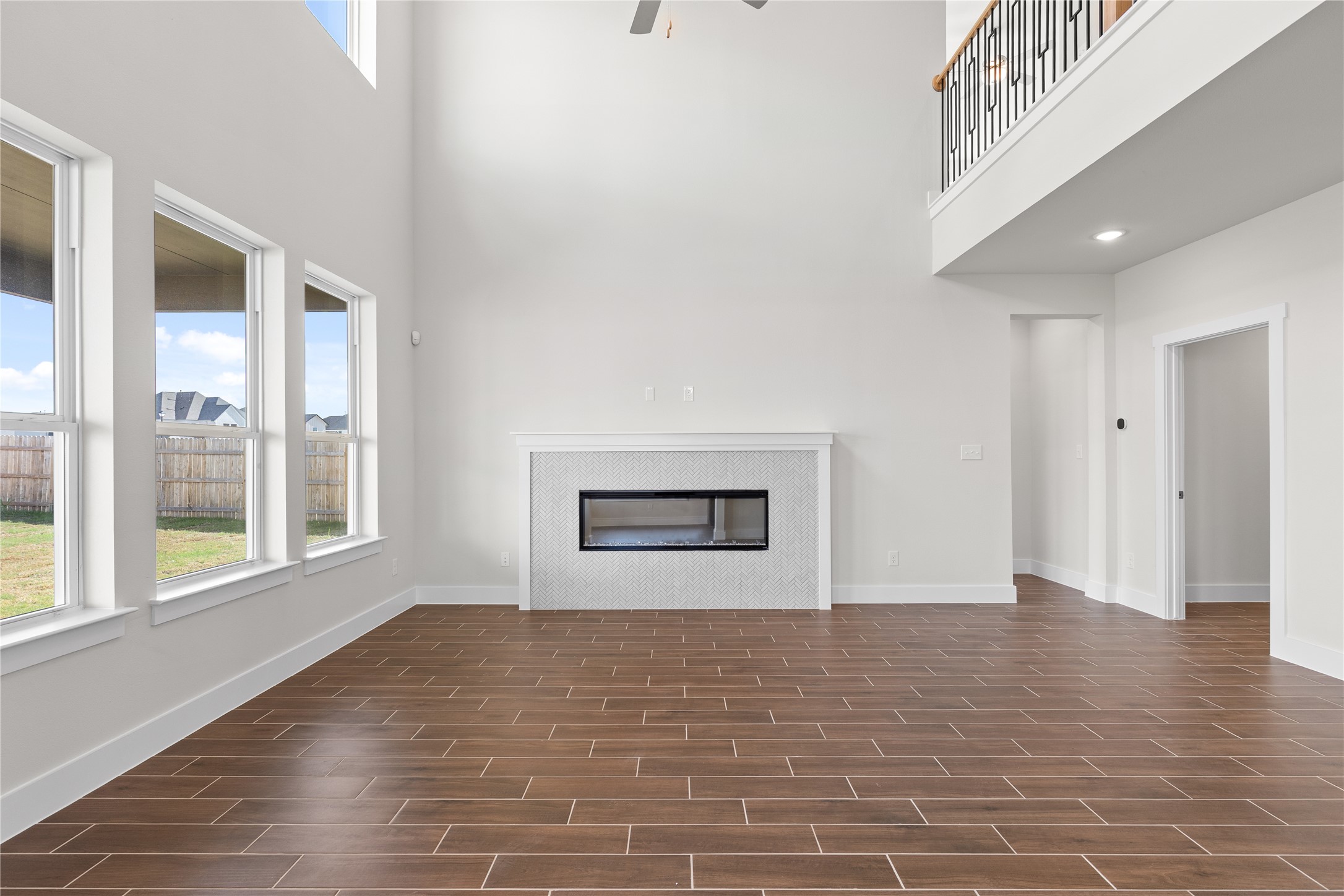 19705 Domino Champ Road Pflugerville, TX 78660 - Photo 13 of 38 Towering ceilings and a modern fireplace anchor this light-filled room finished with plank tile flooring.